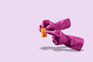 Purple glove holding a big orange battery on light purple background