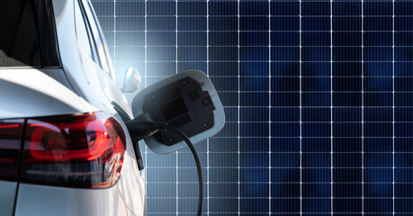 Close up of electric car with a connected charging cable on the background of solar panels	