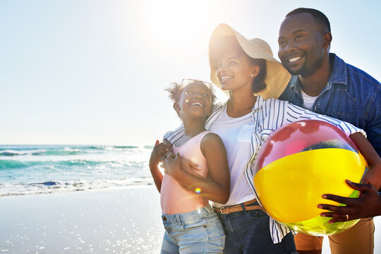 Black Family, Kids Or Beach With A Woman, Man And Girl Child Carrying A Ball While Walking On The Sand By The Sea. Love, Nature And Ocean With A Father, Mother And Daughter On The Coast In Summer