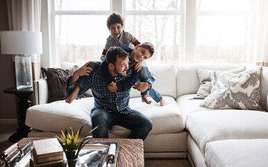 Goofy, funny and bonding father with children on the sofa for playing, quality time and crazy fun. Love, happy and boy kids piling onto dad with energy on the couch of their family home together