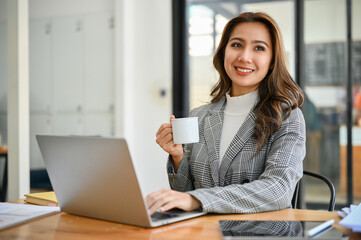 Professional Asian businesswoman or female manager enjoys sipping morning coffee at her desk.