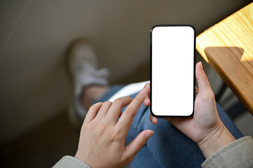 A female using her phone while relaxing in the coffee shop, close-up smartphone mockup. top view - obrazy, fototapety, plakaty