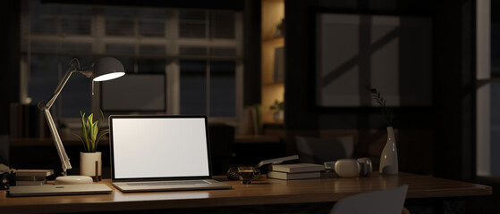 Home workspace at night with laptop mockup, light from table lamp over blurred darkness room