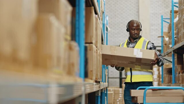 Male warehouse worker using a headset to pick orders and communicate with a warehouse management system. Man using voice directed warehousing technology to fulfil orders for distribution.