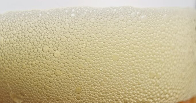 Beer with foam in the glass. Bubbles are bursting. Adding liquid to the glass.