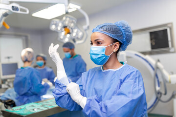Portrait of beautiful female doctor surgeon putting on medical gloves standing in operation room. Surgeon at modern operating room