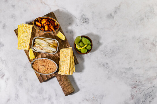 Tinned Fish Board, Variety Of Different Seafood In Conservas. Mediterranean Appetizer Platter With Crackers. Top View, Copy Space.