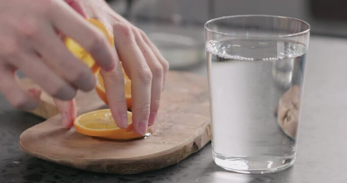Slow motion man put sliced orange lemon into water in glass