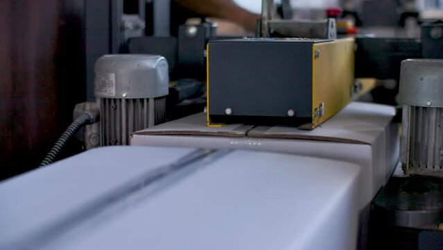 Boxes being closed with adhesive tape by a sealing machine at a factory. Closeup detail shot.
