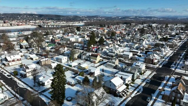 High aerial view of snow covered neighborhood with Susquehanna river and Williamsport Pennsylvania in background. Beautiful blue sky on snowy day.