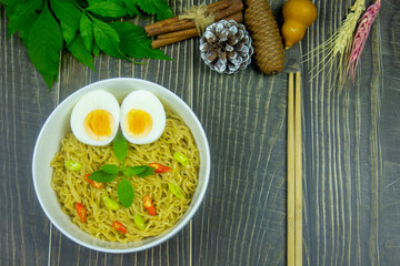 Noodles with Boiled Eggs topping chilli and basil come to serving on dark wood table is my lunch for this meal.