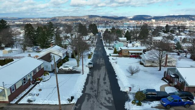 Slow aerial dolly forward over snowy neighborhood. Susquehanna river and Williamsport in distance.
