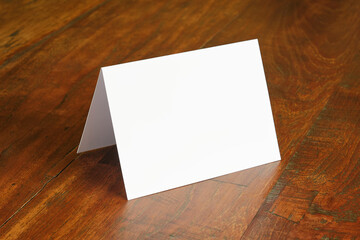 Standing blank empty rectangular greeting card mock up on dark wooden background. For use as a...