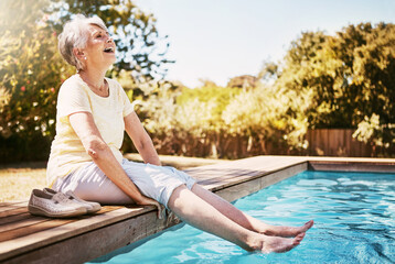 Elderly woman with her feet in the water of the pool while on a vacation, adventure or outdoor trip...