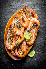 Boiled shrimps on a wooden plate with chopped lime.