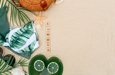 The concept of a holiday by the sea. Seashells, sunglasses, bikinis, flip-flops, starfish and a straw hat on the sand. Background for summer holidays with space for text. View from above.