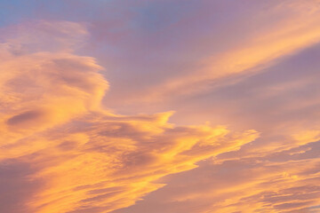 Dramatic cumulus clouds on sunny day at sunset painted in gold with sun. Atmosphere multicolor background or wallpaper