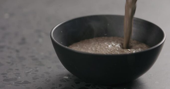 Slow motion pour mushroom cream soup in black bowl with copy space