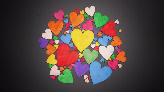 Wooden colored hearts dance on a black background. Stop motion animation for Valentine's Day.