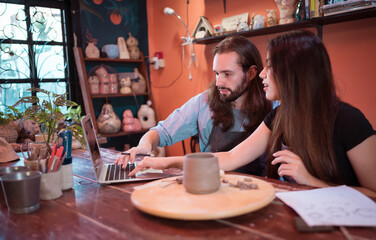 Two young entrepreneurs who own a pottery business. We are discussing the container that the customer wants to be molded. to be used to decorate the house
