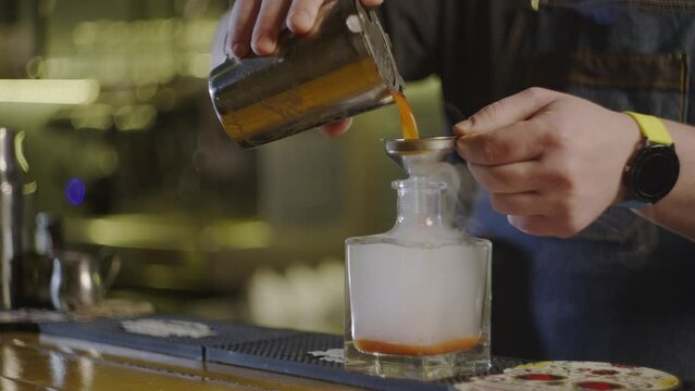 Slow motion video of a bartender pouring cocktail into a bottle. The process of making cocktails with tomato juice and vodka. A professional bartender is preparing a party at the bar. 