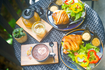 Delicious and stylish served table with coffee and tea, croissant and greens at breakfast
