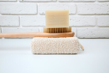 Eco friendly products. Washing brush and natural soap on a wooden tray on a white table. Front view