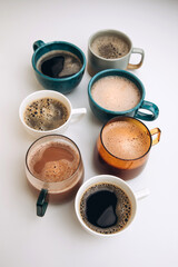 A set of mugs with different coffees on a white background. Flat lay