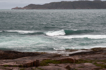 Surf on the coastline of the north sea with a mountainous coast in the background