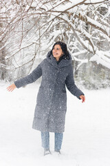 Fototapeta na wymiar Winter portrait of an attractive young woman in a snowy park, outdoors