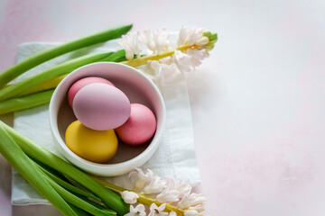 Bunte Ostereier in einer Schüssel und Frühlings Blumen auf einem rosa Hintergrund. Nahaufnahme.