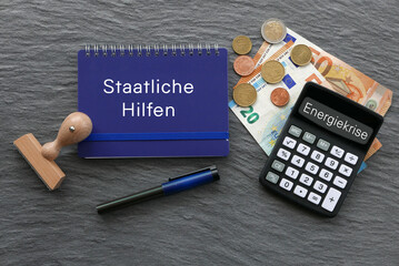  Euroscheine und Taschenrechner mit dem Text Geld Staatliche Hilfen auf einem Notizblock. - obrazy, fototapety, plakaty