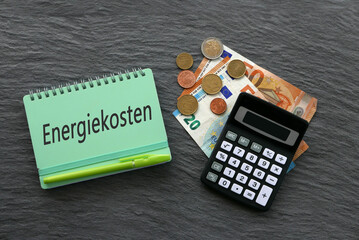 Das Wort Energiekosten ist auf einem Notizblock mit Taschenrechner und Euro-Banknoten abgebildet.
