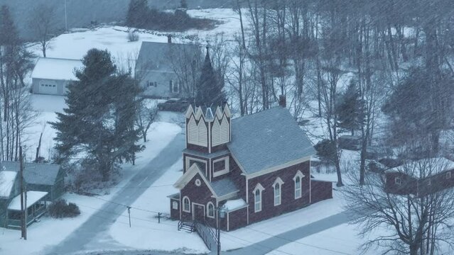 Wide aerial around Swedish Lutheran Church in Monson in snow blizzard
