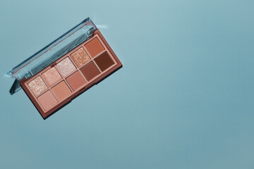 Top view eyeshadow rose gold glitter and beige mauve and brown matte palette on blue background....