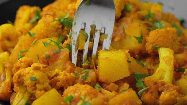 Eating Aloo Gobi traditional Indian dish with fork. Healthy food.
