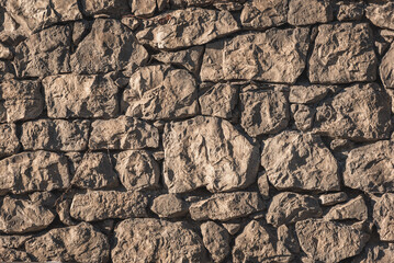 Closeup of wall made of hewn rocks lit with sunlight