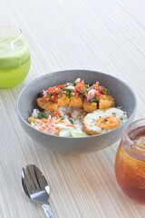 chicken katsu sambal matah with salad and sunny side up egg and drinks on a wooden table.