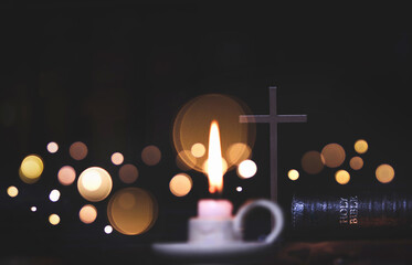 Holy cross of Jesus Christ, bible book and bright Christmas lights bokeh and candles background
