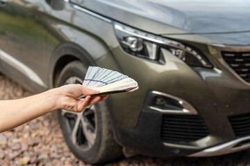 Person with money in the hands standing front car. Insurance, loan concept. Deal of buy or rent new car