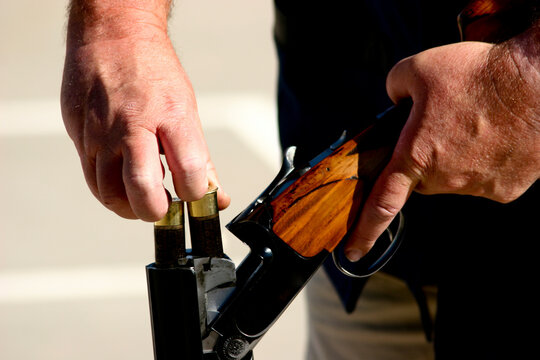 Skeet shooter loads 2 shells in his over/under .12 gauge shotgun.