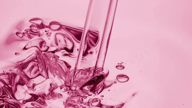 Macro crane shot of pink oil is being poured into pale pink oil on pale pink background | Abstract skincare cosmetics ingredients formulating concept