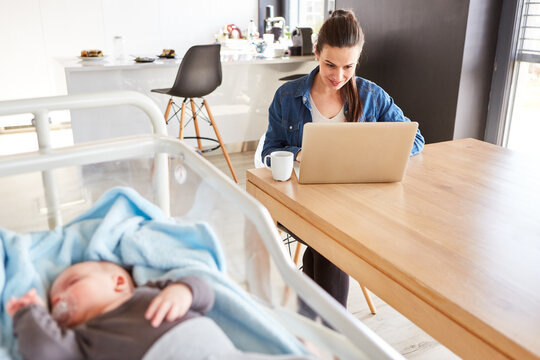 Mutter arbeitet im Home Office mit Baby im Vordergrund