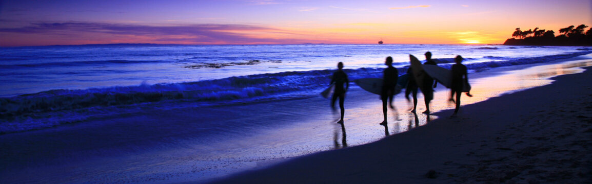 Unknown surfers end the day walking along the beach in Santa Barbara, California, USA