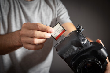 Photographer holding memory card insert DSLR camera.