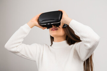 Amazed young girl in virtual reality using VR glasses headset explores metaverse on the white background 