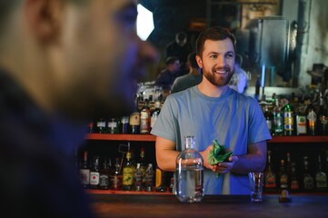 Handsome bar tender standing behind his counter in a pub