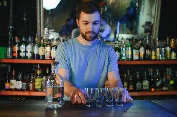 Barman pouring hard spirit into glasses in detail