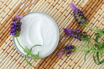 White facial mask (face cream, hair treatment, body butter) in a small jar and lavender flowers. Natural skin and hair care concept. Top view, copy space.
