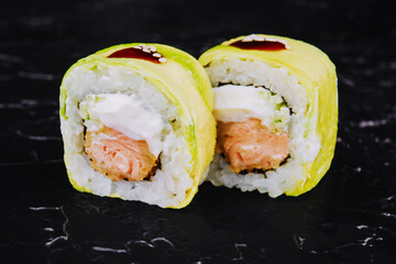 Rolls wrapped in avocado with fried salmon inside